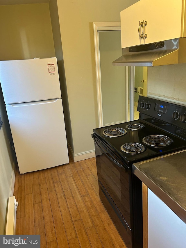 kitchen with white refrigerator, black / electric stove, light hardwood / wood-style floors, and baseboard heating