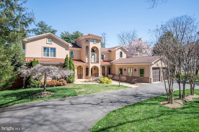 mediterranean / spanish home with a garage and a front lawn