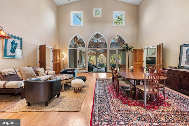 dining room featuring high vaulted ceiling, a healthy amount of sunlight, and light wood-type flooring