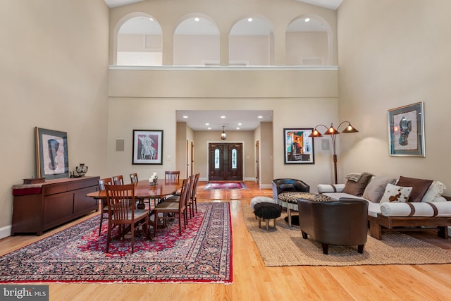 dining area featuring a towering ceiling and wood-type flooring