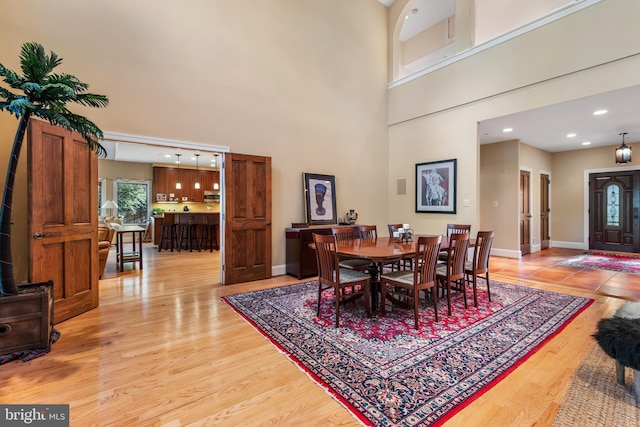 dining space with a towering ceiling and light wood-type flooring