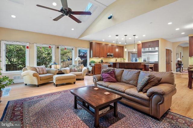 living room featuring ceiling fan, high vaulted ceiling, and light wood-type flooring