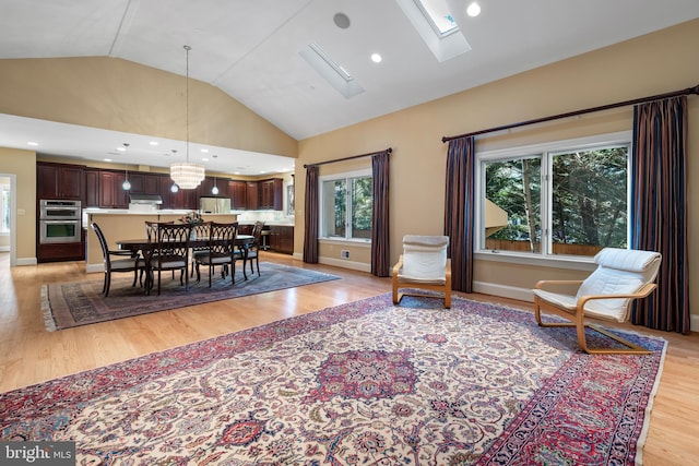 dining room featuring vaulted ceiling with skylight and light hardwood / wood-style floors