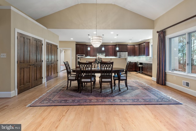 dining room with lofted ceiling, a chandelier, and light hardwood / wood-style floors