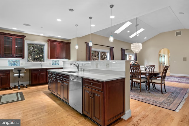 kitchen with lofted ceiling with skylight, sink, a center island, stainless steel dishwasher, and pendant lighting