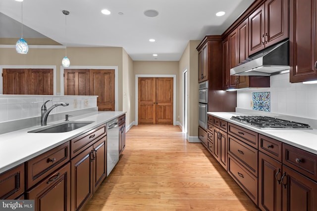 kitchen featuring sink, hanging light fixtures, stainless steel appliances, tasteful backsplash, and light wood-type flooring