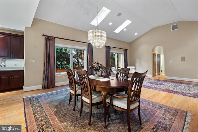 dining space featuring an inviting chandelier, light hardwood / wood-style floors, and vaulted ceiling with skylight