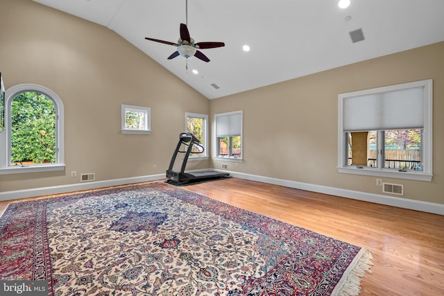 exercise area with ceiling fan, a healthy amount of sunlight, high vaulted ceiling, and light hardwood / wood-style flooring