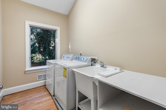 laundry room featuring washing machine and clothes dryer and light hardwood / wood-style floors