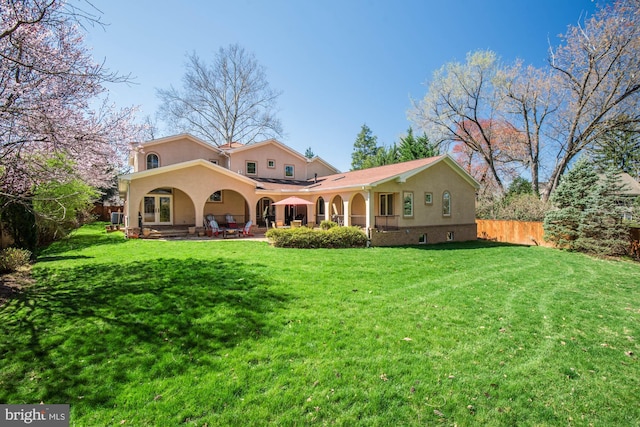 back of property with a yard and a patio