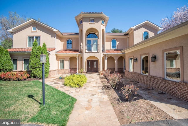 mediterranean / spanish home with a front lawn and a balcony