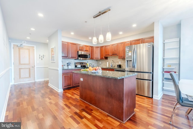 kitchen with a kitchen island, stone countertops, hardwood / wood-style floors, pendant lighting, and stainless steel appliances