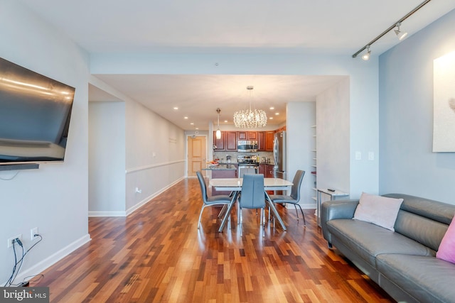 dining space featuring a notable chandelier, dark wood-type flooring, and track lighting