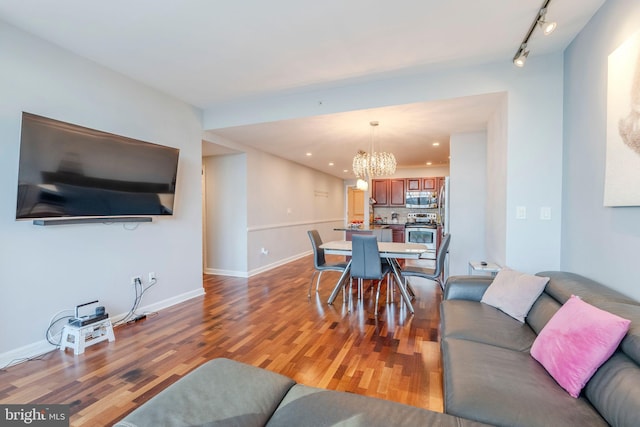 living room with hardwood / wood-style flooring, rail lighting, and an inviting chandelier