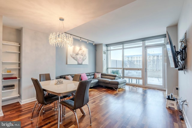 dining room featuring rail lighting, dark wood-type flooring, floor to ceiling windows, and a chandelier