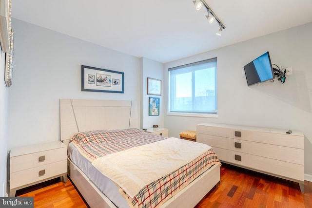 bedroom featuring track lighting and dark hardwood / wood-style flooring