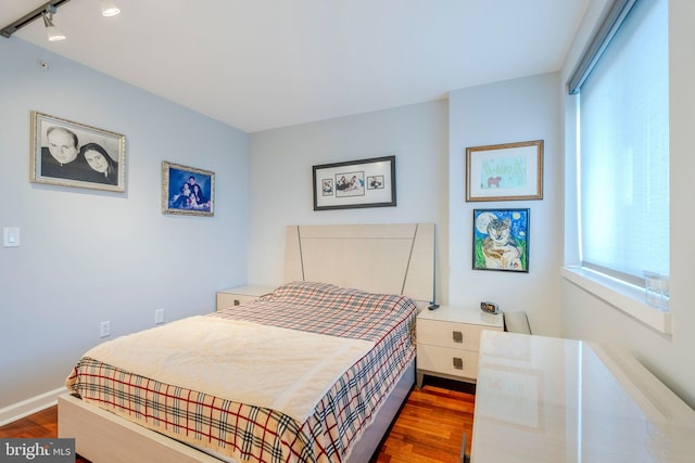 bedroom with track lighting and dark hardwood / wood-style floors