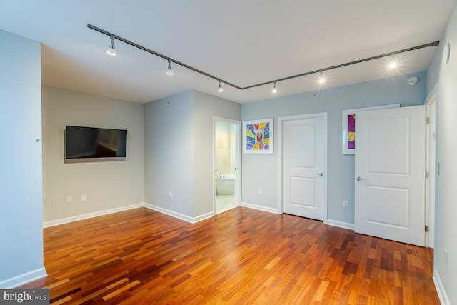 empty room with wood-type flooring and rail lighting