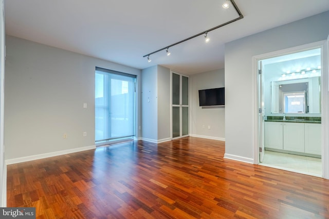 unfurnished room featuring wood-type flooring, rail lighting, and sink