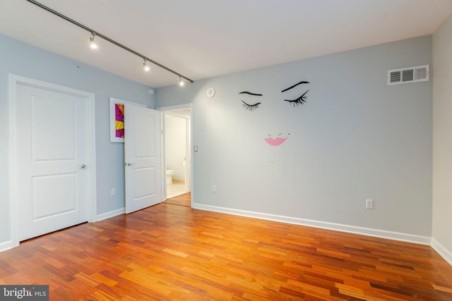 empty room with light hardwood / wood-style flooring and track lighting