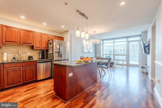 kitchen featuring sink, a center island, dark stone counters, pendant lighting, and stainless steel appliances