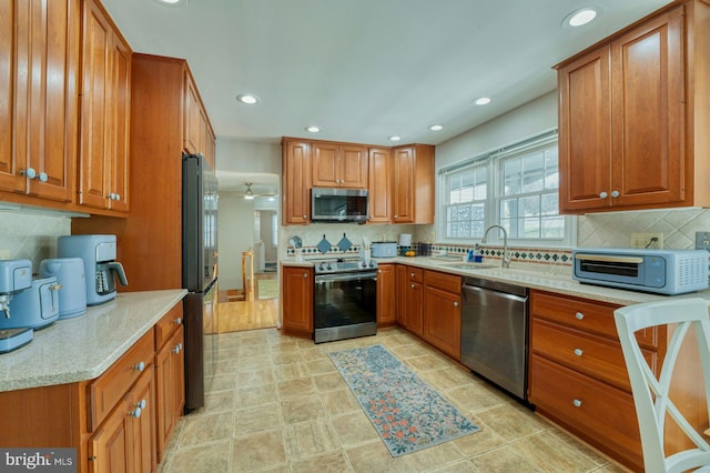 kitchen with tasteful backsplash, appliances with stainless steel finishes, sink, and light stone counters