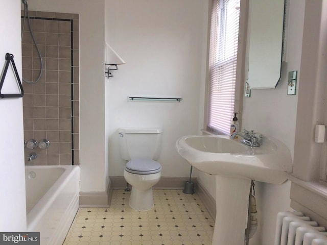 bathroom featuring radiator, tiled shower / bath combo, and toilet