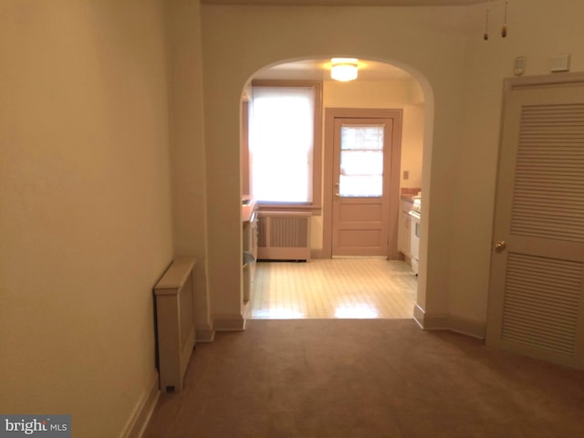 hall featuring light carpet and radiator