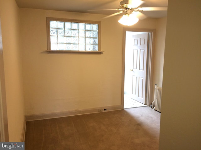 carpeted empty room with radiator heating unit and ceiling fan