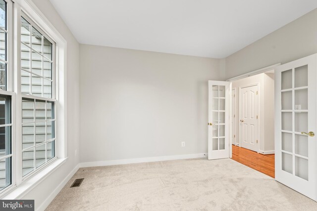 empty room with baseboards, visible vents, carpet flooring, and french doors