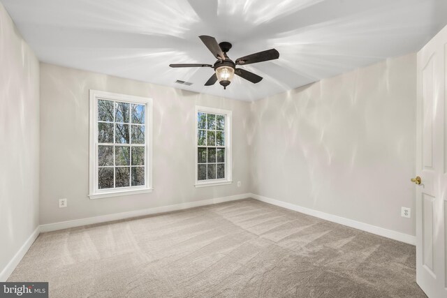 carpeted spare room with ceiling fan, visible vents, and baseboards