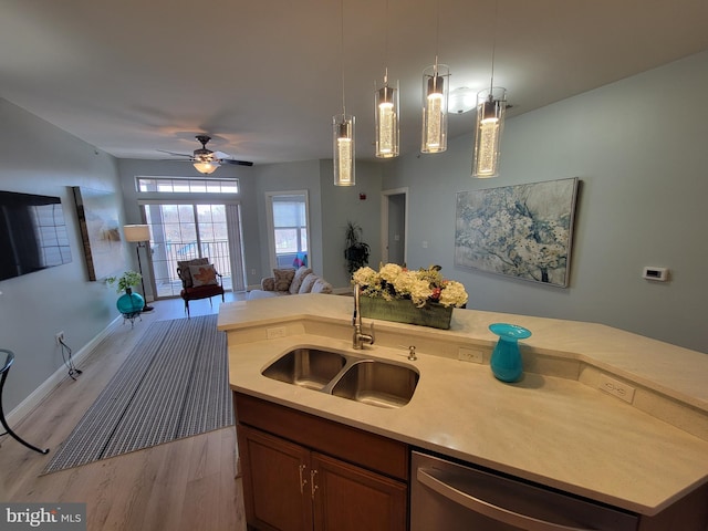 kitchen with a center island with sink, dishwasher, sink, and pendant lighting