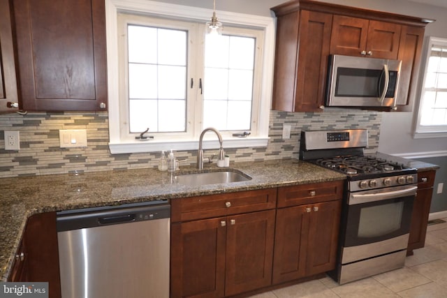 kitchen with light tile patterned flooring, sink, tasteful backsplash, appliances with stainless steel finishes, and dark stone counters