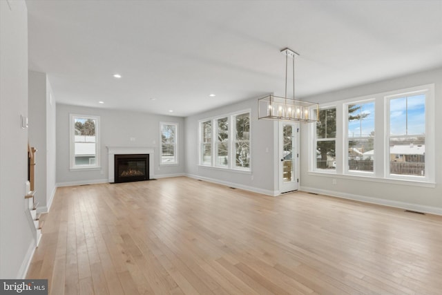 unfurnished living room featuring light hardwood / wood-style floors and a notable chandelier