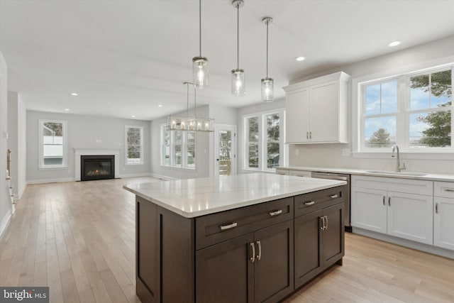 kitchen with pendant lighting, sink, plenty of natural light, dark brown cabinetry, and white cabinets