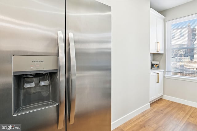 kitchen with white cabinetry, stainless steel fridge, and light hardwood / wood-style flooring