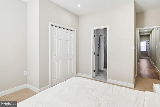 carpeted bedroom with ensuite bathroom and a closet