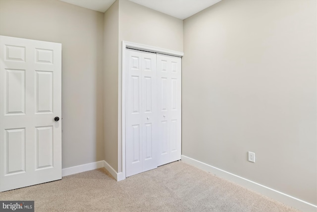 unfurnished bedroom with light carpet and a closet