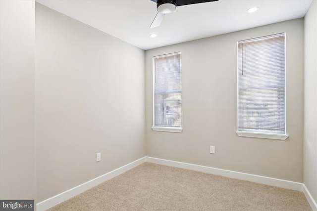 carpeted spare room featuring a wealth of natural light and ceiling fan