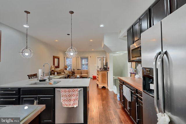 kitchen with dark wood-type flooring, appliances with stainless steel finishes, sink, and hanging light fixtures