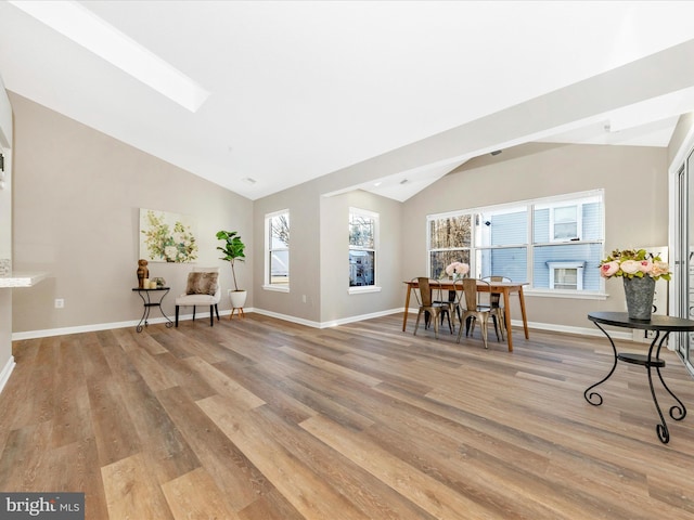 dining area with lofted ceiling with skylight and light hardwood / wood-style flooring