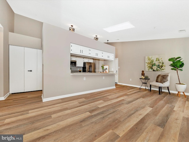 unfurnished living room featuring light hardwood / wood-style floors and a skylight