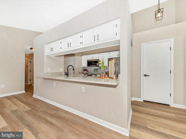 kitchen with sink, light stone counters, light wood-type flooring, appliances with stainless steel finishes, and white cabinets