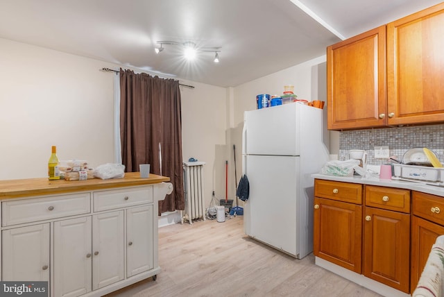 kitchen with light hardwood / wood-style flooring, radiator heating unit, tasteful backsplash, and white fridge