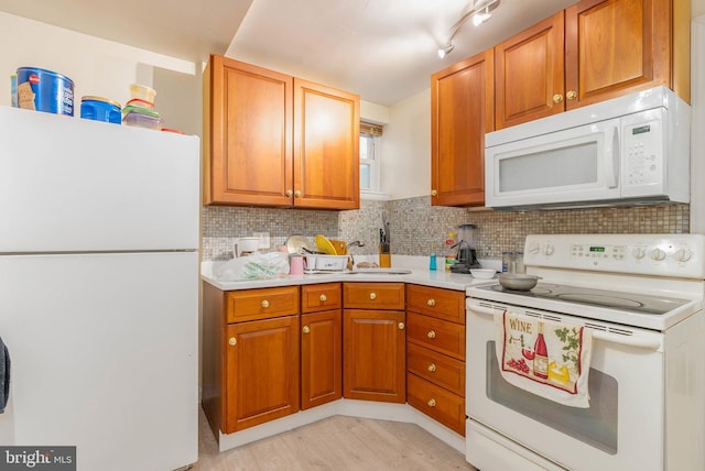 kitchen with light hardwood / wood-style floors, white appliances, and decorative backsplash