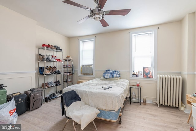 bedroom with radiator, cooling unit, ceiling fan, and light hardwood / wood-style flooring