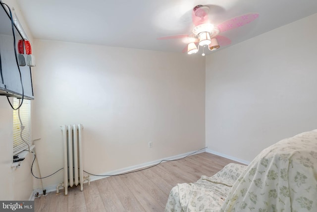 living area with radiator heating unit, ceiling fan, and light wood-type flooring