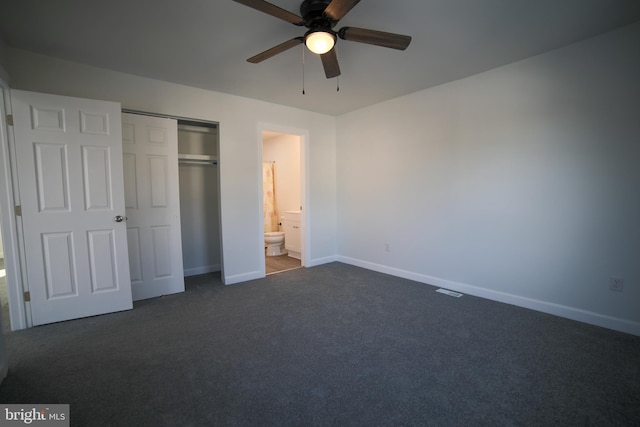 unfurnished bedroom with dark colored carpet, connected bathroom, ceiling fan, and a closet