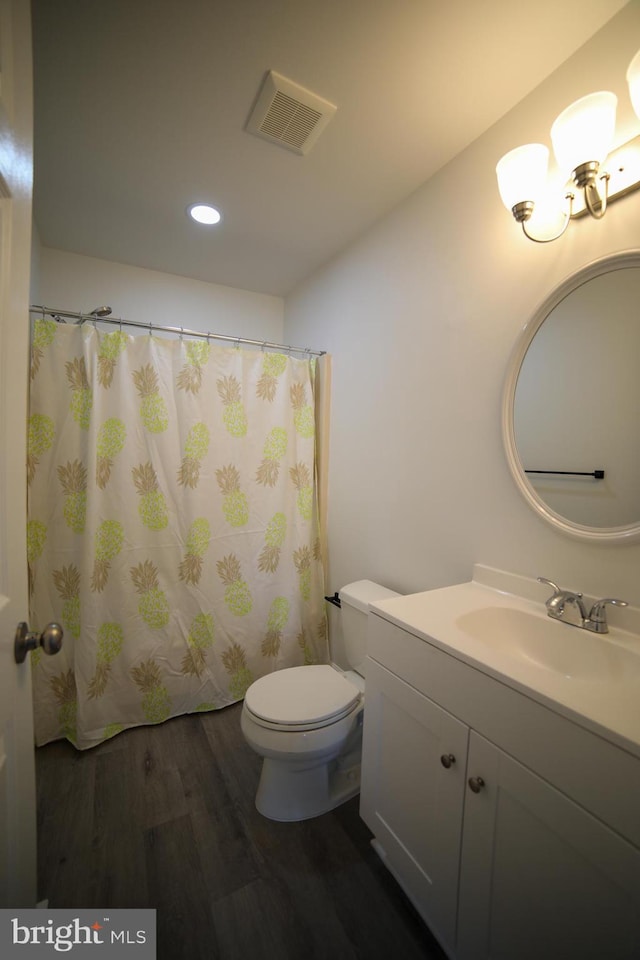 bathroom with wood-type flooring, vanity, and toilet