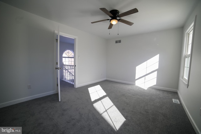 empty room featuring dark colored carpet and ceiling fan